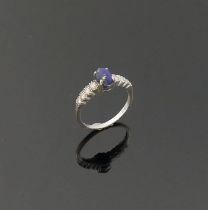 An 18 carat white gold lapis lazuli and diamond ring, the oval lapis lazuli cabochon in four claw