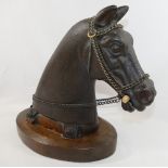 A 20th century cast iron horses head, mounted to an oval oak plinth, with steel chain reins and