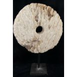 A large coral circular carved disc with central hole, (similar to that of a rai stone), raised on