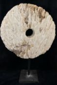 A large coral circular carved disc with central hole, (similar to that of a rai stone), raised on