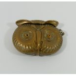 A novelty brass vesta in the form of the head of an owl, with amber glass eyes and match strike to