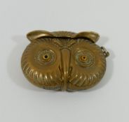 A novelty brass vesta in the form of the head of an owl, with amber glass eyes and match strike to