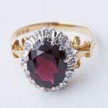 An 18ct yellow & white gold cluster ring set with a central oval cut garnet, approx. 2.80 carats
