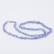 An 18" string of oval cut tanzanite beads strung to a 9ct white gold clasp, 16.70gm.