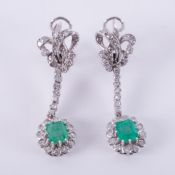 An ornate pair of white metal drop earrings set with emerald cut emeralds, total emerald weight