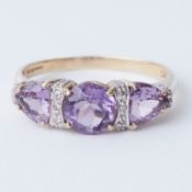 A 9ct yellow gold ring set with a central round cut amethyst with a triangular shaped amethyst set