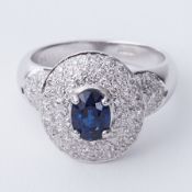 An 18ct white gold modern cluster style ring set with a central oval cut blue sapphire, approx. 0.80