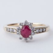 A 9ct yellow gold cluster ring set with a central oval cut ruby, approx. 0.30 carats, surrounded
