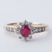 A 9ct yellow gold cluster ring set with approx. 0.30 carat oval cut ruby & approx. 0.20 carats of