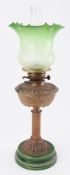 A Victorian brass oil lamp with green etched glass shade.