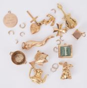 A quantity of 9ct yellow gold charms to include a guitar, dice, fish with pearl, heart, anchor &