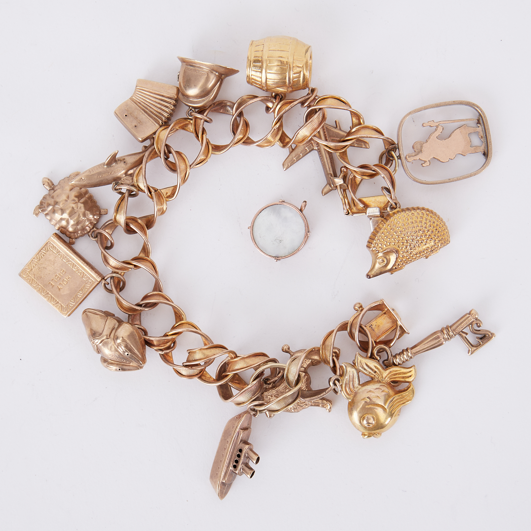 A 9ct yellow gold charm bracelet with fifteen charms (one loose), all hallmarked apart from the