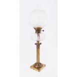 A Victorian oil lamp on brass column with glass reservoir and embossed shade.