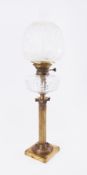 A Victorian oil lamp on brass column with glass reservoir and embossed shade.