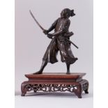 A Japanese Meiji bronze Samurai warrior on carved hardwood stand, overall height 36cm.