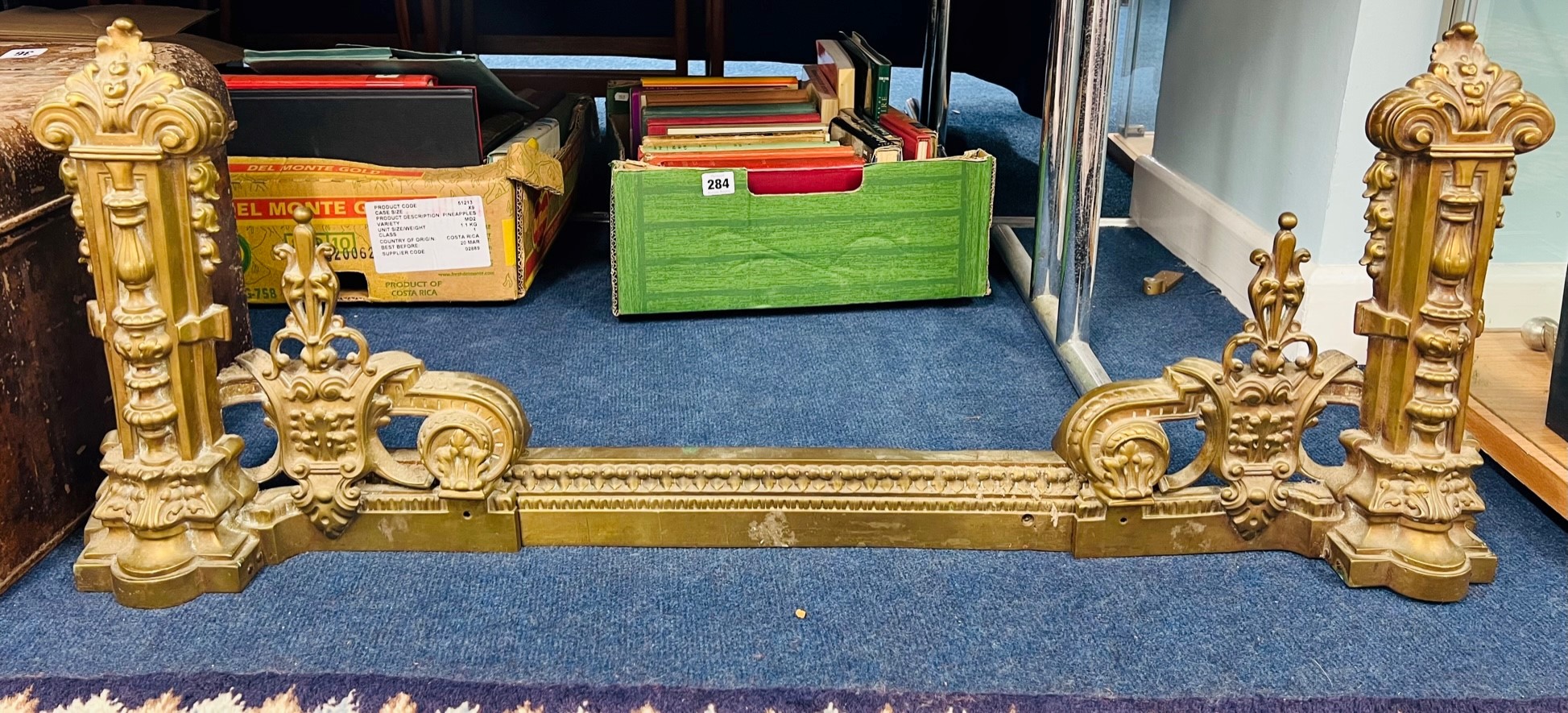 An antique brass extending ornate fender.