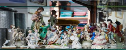 A mixed collection of continental porcelain figures including Cupid, Meissen style dancing groups