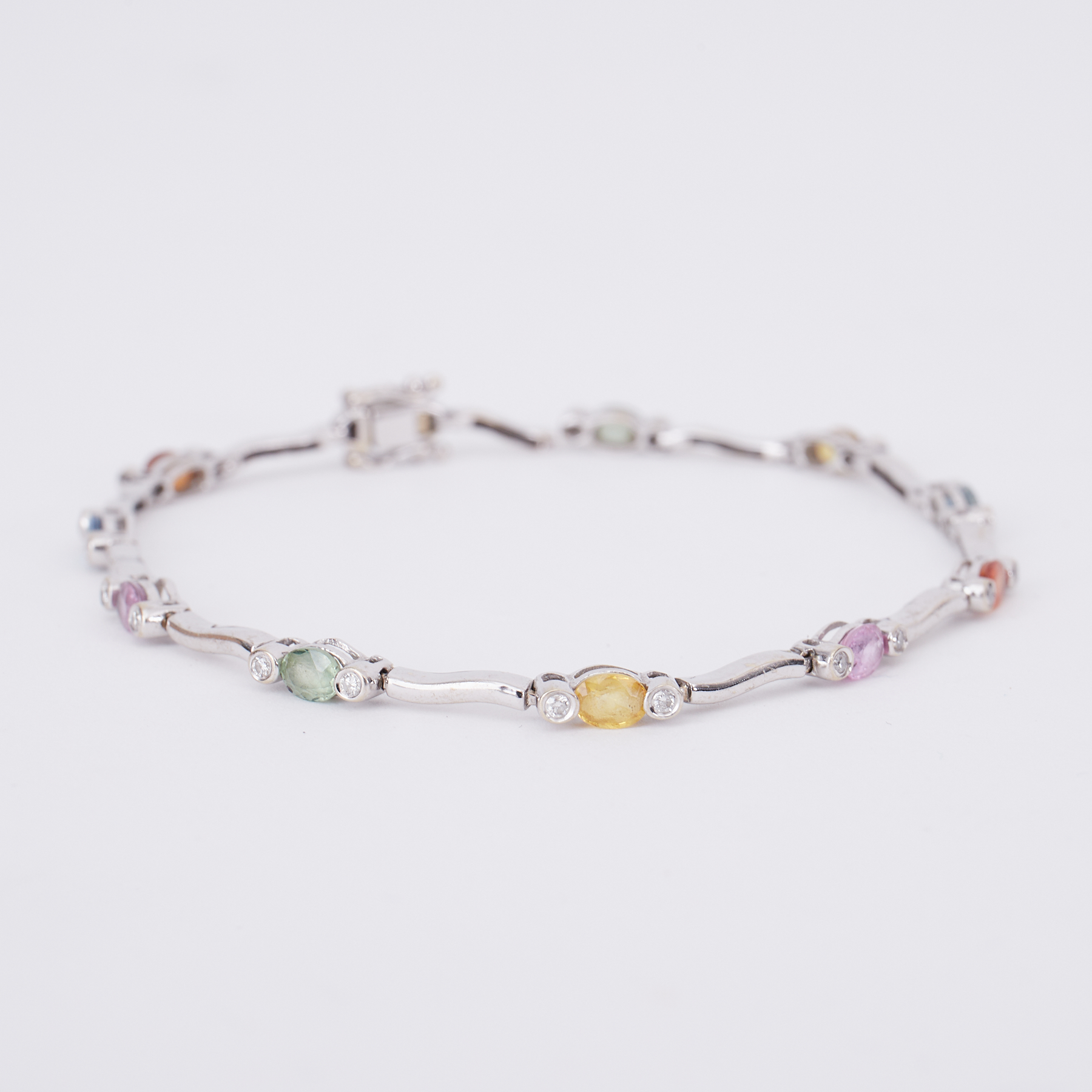 A white gold bracelet set with oval cut multi-coloured sapphires set in between small round