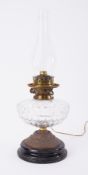 A squat Victorian oil lamp with clear glass reservoir and no shade.