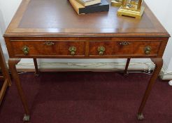 A 20th century walnut two drawer writing table on shaped legs with claw ball feet, width 93cm.
