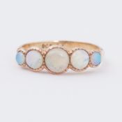 An antique 9ct yellow gold five stone ring set with five graduated cabochon cut opals in a