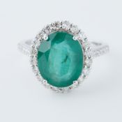 An 18ct white gold cluster ring set with an oval cut emerald, approx. 4.50 carats, surrounded by