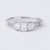 An 18ct white gold ring set centrally with three emerald cut diamonds, total weight of emerald cut