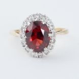 An 18ct yellow & white gold cluster ring set with a central oval cut garnet, approx. 2.23 carats,
