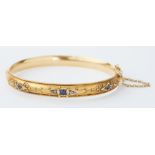 An antique 9ct yellow gold hinged bangle with filigree decoration and set with three round cut