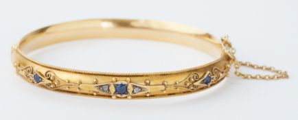 An antique 9ct yellow gold hinged bangle with filigree decoration and set with three round cut