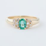 An 18ct yellow gold ring set with an oval cut emerald, approx. 0.42 carats, set with five small