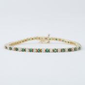 A 14ct yellow gold line bracelet with alternating round cut emeralds & diamonds in an illusion
