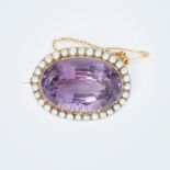 A yellow gold oval shaped brooch set with a central large oval cut amethyst, approx. 30 carats,