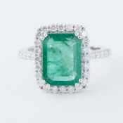 An 18ct white gold cluster ring set with a central emerald cut emerald, approx. 4.91 carats,