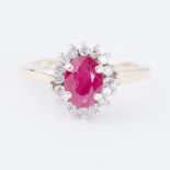 A 9ct yellow gold cluster ring set with a central oval cut ruby, approx. 0.75 carats, surrounded