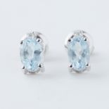 A pair of white gold studs set with an oval cut aquamarine with a small round brilliant cut