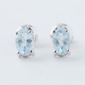 A pair of white gold studs set with an oval cut aquamarine with a small round brilliant cut