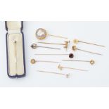 A collection of eleven gold stick pins, including a boxed diamond stick pin, others set with pearls,