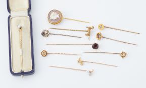 A collection of eleven gold stick pins, including a boxed diamond stick pin, others set with pearls,