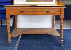 An Edwardian desk fitted with two drawers, on turned legs; used in the studio.