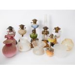 A collection of Victorian and later oil lamps coloured and other glass shades, ornate brass