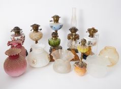 A collection of Victorian and later oil lamps coloured and other glass shades, ornate brass