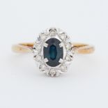 An 18ct yellow gold ring set with a central oval cut sapphire surrounded by small round cut diamonds
