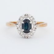 An 18ct yellow gold ring set with a central oval cut sapphire surrounded by small round cut diamonds