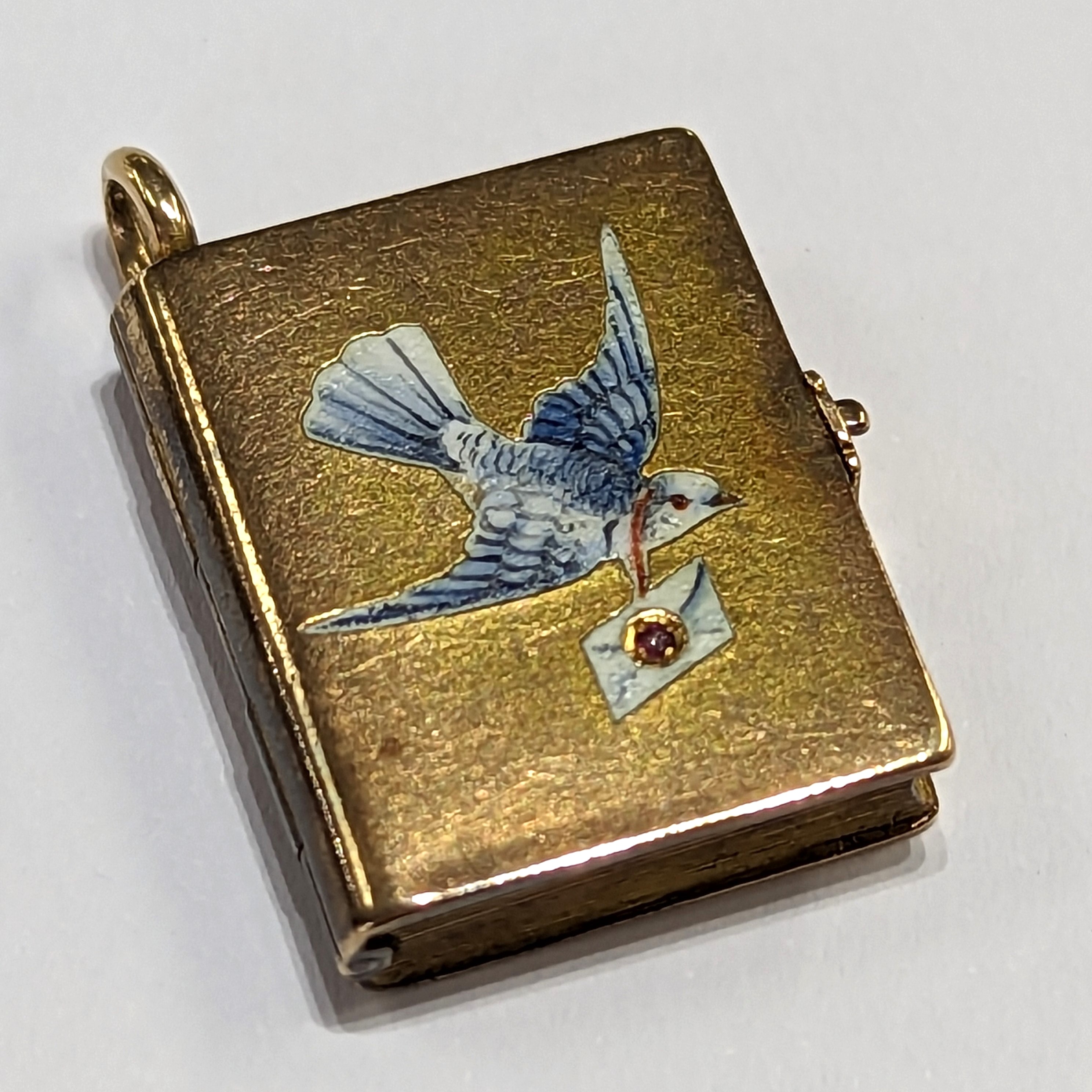 A gold locket in the shape of a book inset with a Dove & envelope set with a small ruby, measuring - Image 2 of 5