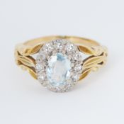 An 18ct yellow & white gold cluster ring set with an oval cut aquamarine surrounded by small round