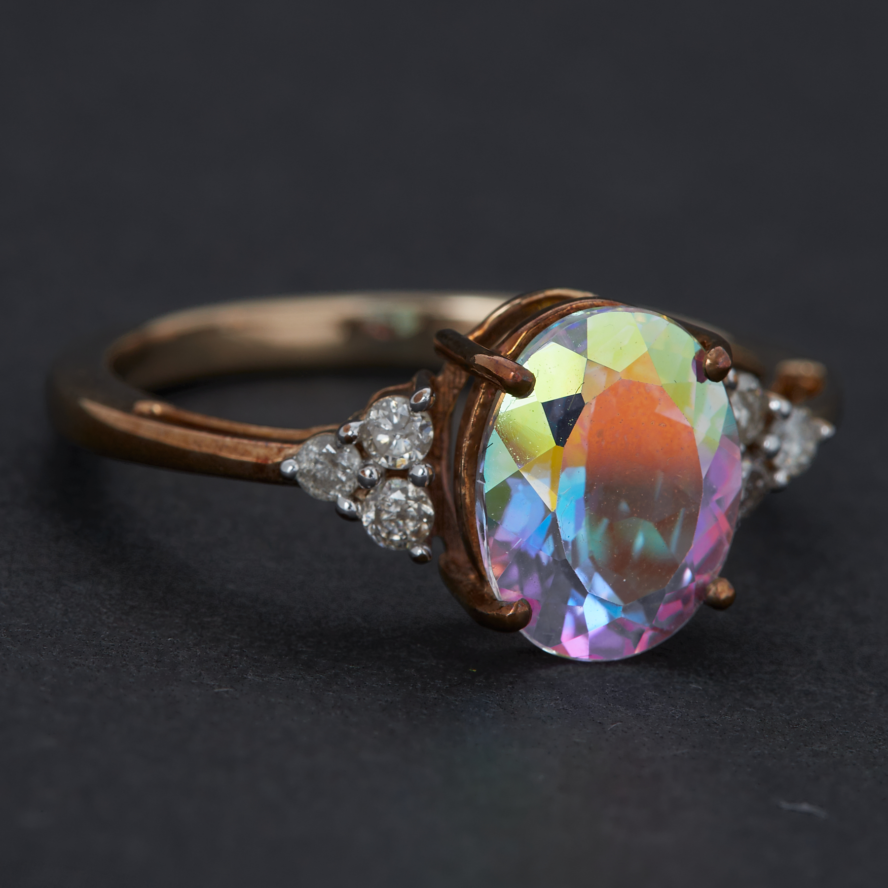 A 9ct yellow gold ring set with 3,13 carats of oval cut mystic topaz with a trefoil of round cut