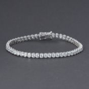 A 9ct white gold line bracelet (stamped 9k) set with round brilliant cut crystals, push in clasp &