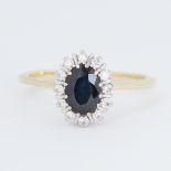 An 18ct yellow & white gold cluster ring set with a central oval cut dark blue sapphire and