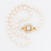 An 18" string of 8mm cultured pearls on a 18ct yellow gold diamond set circular design clasp, 50.